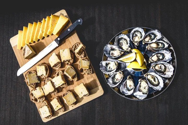 Een selectie van kaas op brood en verse oesters op een tafel.