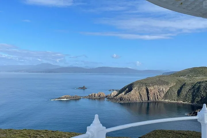 Vue panoramique sur le littoral accidenté et l'océan depuis le balcon du phare.